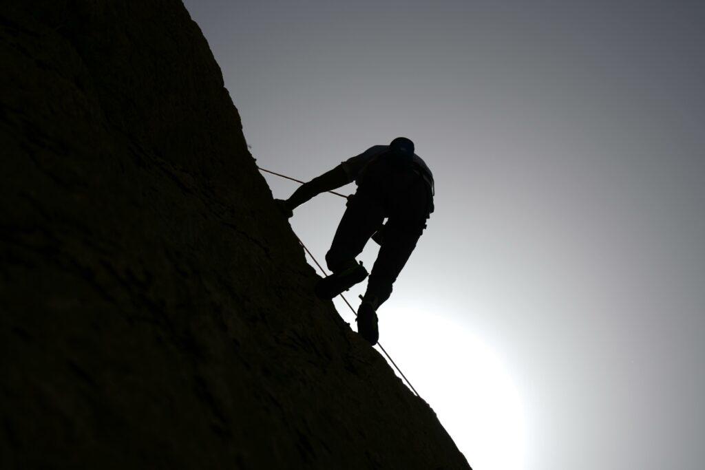 Silhouette of a climber scaling a rocky wall against the rising sun in Damascus, Syria.